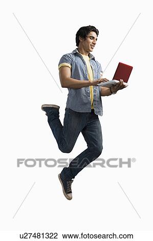 Stock Image - Man working on a laptop and jumping. Fotosearch