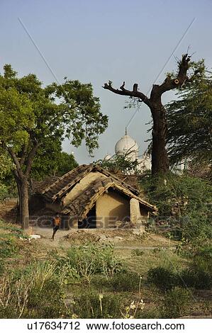 Stock Image - Mud huts with mausoleum in the background, Taj Mahal, Agra, Uttar Pradesh, India. Fotosearch
