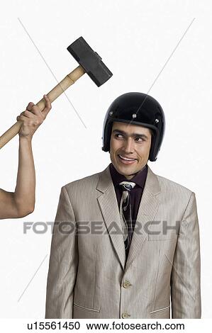 Person's hand hitting a hammer on a businessman wearing a helmet View Large Photo Image Stock Image - Person's hand hitting a hammer on a businessman wearing a helmet. Fotosearch