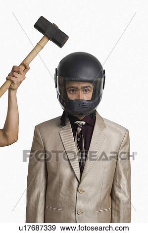 Person's hand hitting a hammer on a businessman wearing a helmet View Large Photo Image Stock Photo - Person's hand hitting a hammer on a businessman wearing a helmet. Fotosearch