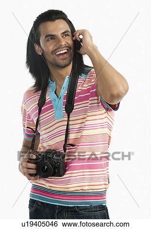 Stock Photograph - Photographer holding a digital camera and talking on a mobile phone. Fotosearch