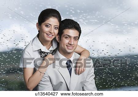 Stock Photo - Portrait of a business couple smiling in front of a glass with water droplets. Fotosearch