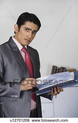 Stock Photo - Portrait of a businessman doing paperwork in an office. Fotosearch