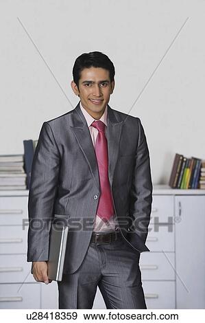 Portrait of a businessman holding a laptop and smiling View Large Photo Image Stock Photo - Portrait of a businessman holding a laptop and smiling. Fotosearch