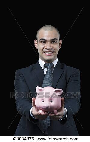 Portrait of a businessman holding a piggy bank View Large Photo Image Stock Photograph - Portrait of a businessman holding a piggy bank. Fotosearch