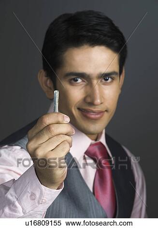 Stock Photography - Portrait of a businessman holding a rolled up paper. Fotosearch
