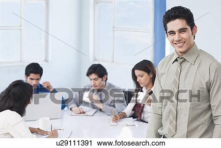 Portrait of a businessman smiling with his colleagues in a meeting View Large Photo Image Stock Image - Portrait of a businessman smiling with his colleagues in a meeting. Fotosearch