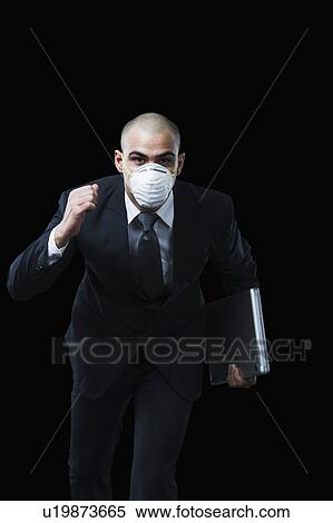 Stock Photography - Portrait of a businessman wearing a pollution mask and running. Fotosearch