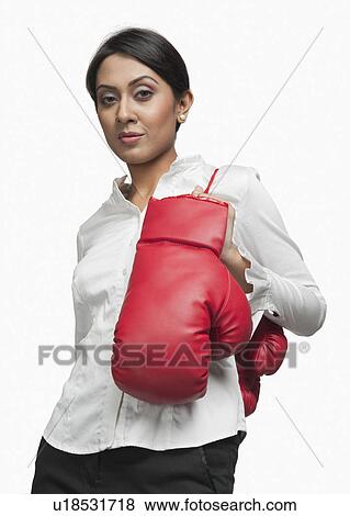 Stock Photo - Portrait of a businesswoman carrying boxing gloves on her shoulder. Fotosearch