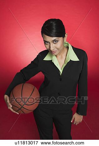 Stock Photo - Portrait of a businesswoman holding a basketball. Fotosearch