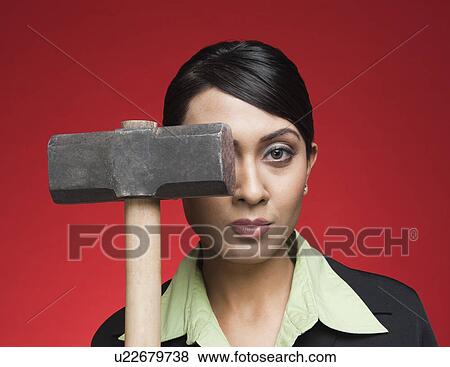 Stock Photo - Portrait of a businesswoman holding a sledgehammer. Fotosearch
