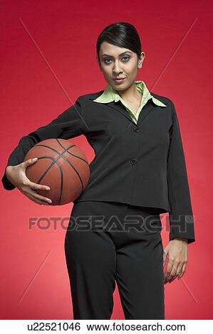 Stock Photograph - Portrait of a businesswoman holding a basketball. Fotosearch