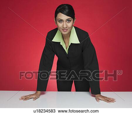 Stock Image - Portrait of a businesswoman standing at a conference table. Fotosearch