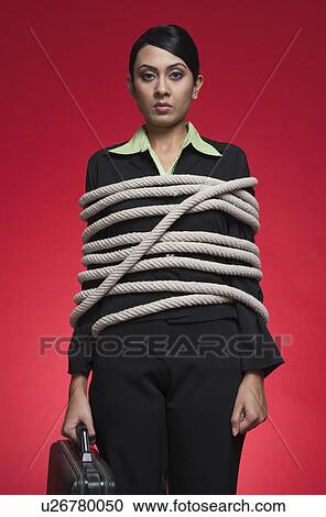 Stock Image - Portrait of a businesswoman tied up with rope. Fotosearch