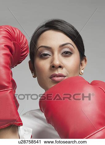 Stock Image - Portrait of a businesswoman wearing boxing gloves. Fotosearch