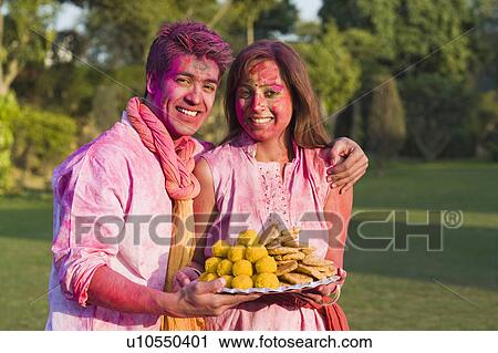 Portrait of a couple holding a plate of sweets on Holi View Large Photo Image Stock Image - Portrait of a couple holding a plate of sweets on Holi. Fotosearch