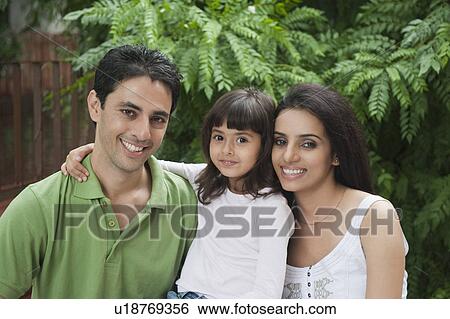 Stock Photograph - Portrait of a couple smiling with their daughter. Fotosearch