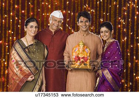 Stock Image - Portrait of a family holding an idol of lord Ganesha. Fotosearch
