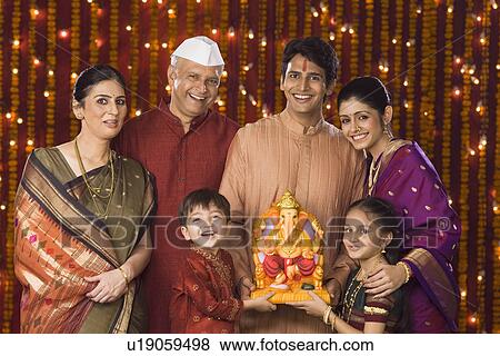 Stock Photo - Portrait of a family holding an idol of lord Ganesha. Fotosearch