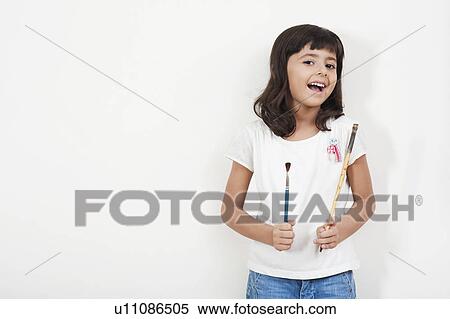 Stock Photography - Portrait of a girl holding paintbrushes. Fotosearch