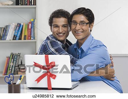 Stock Image - Portrait of a man and his son hugging each other. Fotosearch