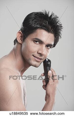Stock Photography - Portrait of a man shaving with electric razor. Fotosearch