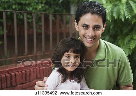 Stock Image - Portrait of a man smiling with his daughter. Fotosearch