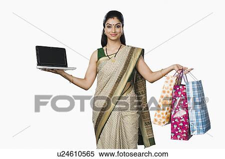 Portrait of a woman holding a laptop and shopping bags View Large Photo Image Stock Photography - Portrait of a woman holding a laptop and shopping bags. Fotosearch