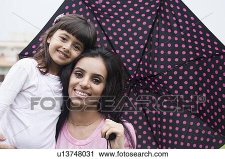 Portrait of a woman holding an umbrella with her daughter View Large Photo Image Stock Image - Portrait of a woman holding an umbrella with her daughter. Fotosearch
