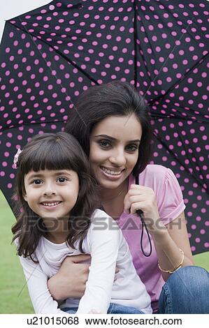 Stock Photo - Portrait of a woman holding an umbrella with her daughter. Fotosearch