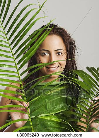 Stock Image - Portrait of a woman holding leaves. Fotosearch