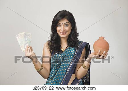 Stock Image - Portrait of a woman holding money and a piggybank. Fotosearch