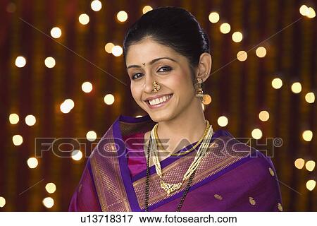 Stock Photo - Portrait of a woman smiling in front of Diwali decoration. Fotosearch