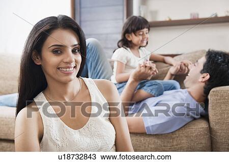 Stock Image - Portrait of a woman smiling with her family in the background. Fotosearch