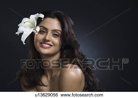 Stock Photograph - Portrait of a woman wearing a Tiger Lily flower and smiling. Fotosearch
