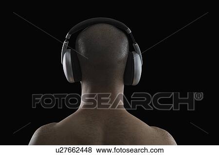 Rear view of a man listening to headphones View Large Photo Image Stock Photo - Rear view of a man listening to headphones. Fotosearch