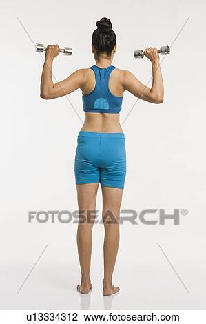 Rear view of a woman exercising with dumbbells View Large Photo Image Stock Image - Rear view of a woman exercising with dumbbells. Fotosearch