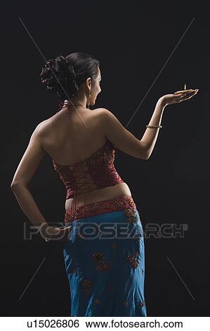 Rear view of a woman holding an oil lamp View Large Photo Image Stock Photograph - Rear view of a woman holding an oil lamp. Fotosearch