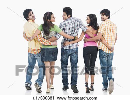 Stock Image - Rear view of college students walking with their arms around each other. Fotosearch