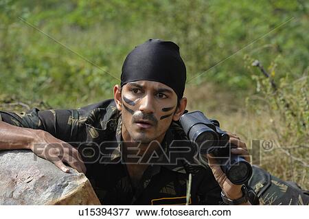 Stock Photo - Soldier hiding behind a rock with binoculars. Fotosearch