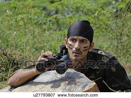 Stock Photo - Soldier hiding behind a rock with binoculars. Fotosearch