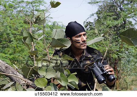 Soldier holding binoculars in a forest View Large Photo Image Stock Image - Soldier holding binoculars in a forest. Fotosearch