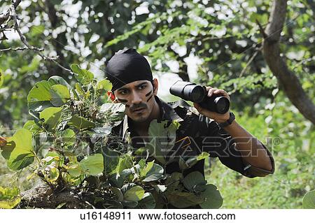 Soldier holding binoculars in a forest View Large Photo Image Stock Image - Soldier holding binoculars in a forest. Fotosearch