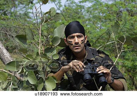 Soldier holding binoculars in a forest View Large Photo Image Stock Image - Soldier holding binoculars in a forest. Fotosearch