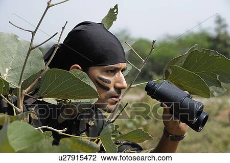 Soldier holding binoculars in a forest View Large Photo Image Stock Image - Soldier holding binoculars in a forest. Fotosearch