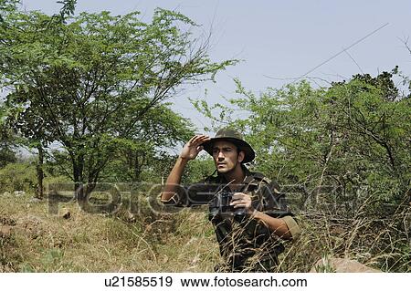 Soldier holding binoculars in a forest View Large Photo Image Stock Photo - Soldier holding binoculars in a forest. Fotosearch
