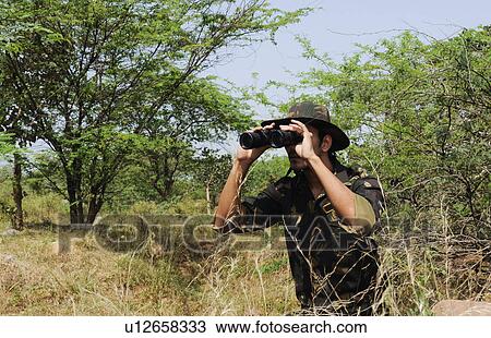 Soldier looking through binoculars in a forest View Large Photo Image Stock Image - Soldier looking through binoculars in a forest. Fotosearch