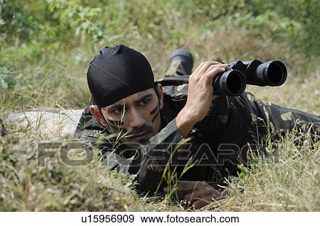 Stock Photo - Soldier looking through binoculars in a forest. Fotosearch