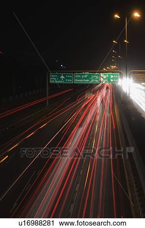 Stock Image - Streaks of the tail lights of moving vehicles on the road, National Highway 8, Gurgaon, Haryana, India. Fotosearch