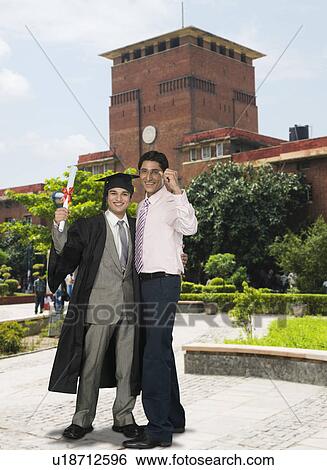 Stock Photograph - Student standing with his father holding his diploma. Fotosearch